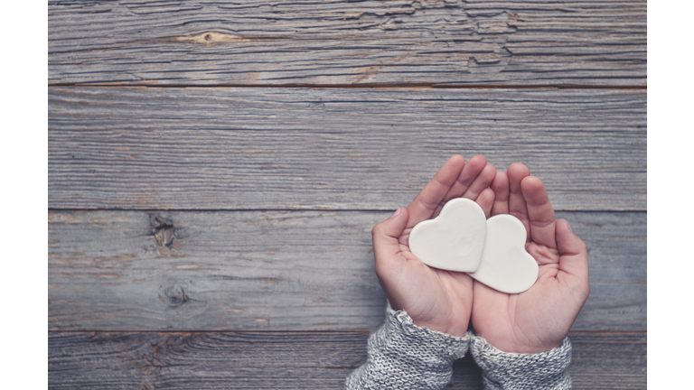 Woman holding two white love hearts.