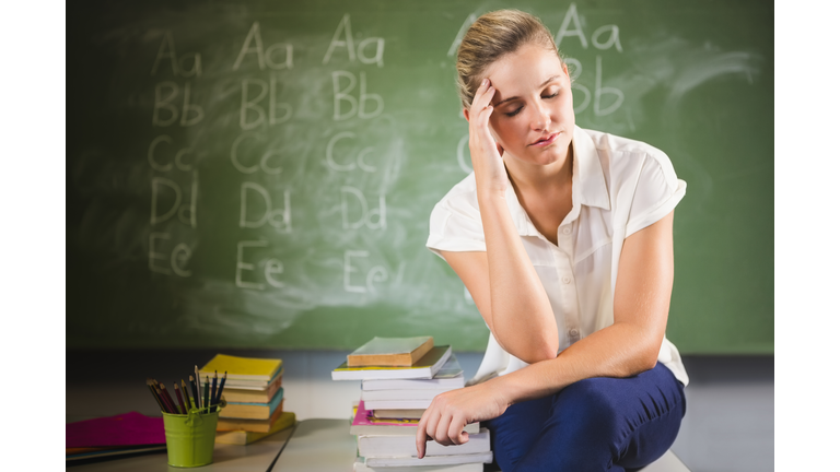 Tensed school teacher sitting in classroom