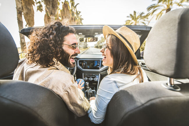 Happy couple driving convertible car enjoying summer vacation - Friends rent cabrio auto on holiday - Roadtrip, freedom, travel and transport rental service concept