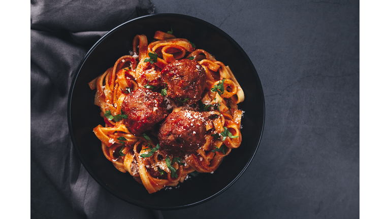 Tagliatelle  with meatballs and  tomato sauce on black background.