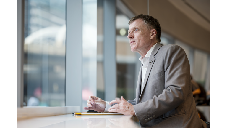 Successful of Senior Businessman sitting in cafe of hotel lounge while looking through a windows.