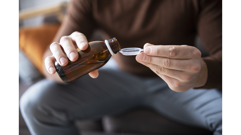 Man pouring cough syrup into spoon.