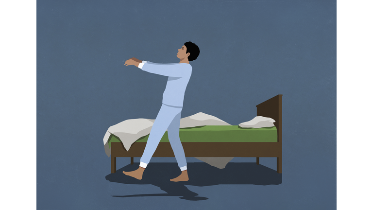 Man in pajamas sleepwalking along bed in nighttime bedroom