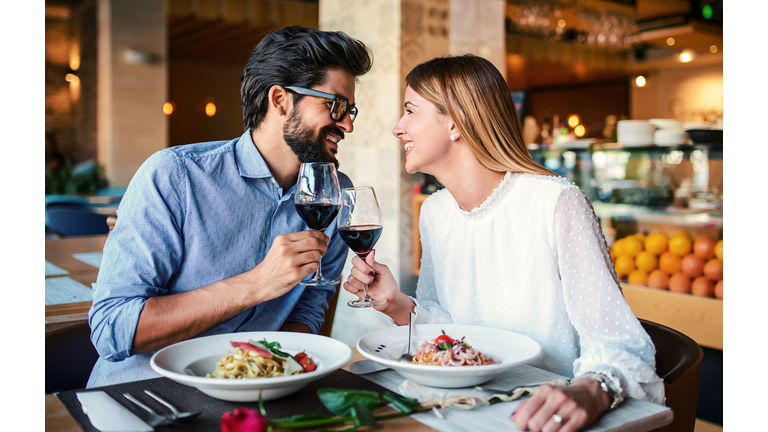 Paste and red wine. Young couple enjoying lunch in the restaurant. Lifestyle, love, relationships, food concept