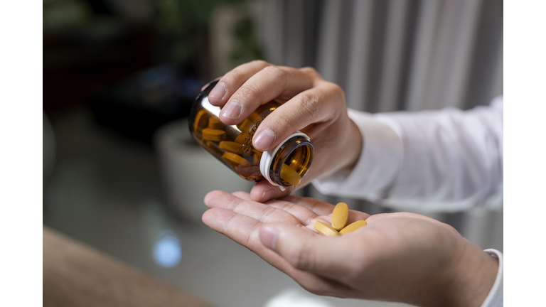 Close up of human hands. He is taking pill