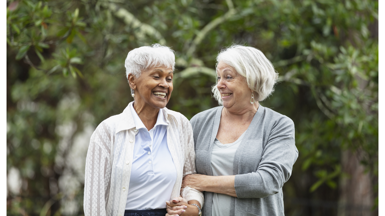 Senior women walking, talking in back yard, smiling