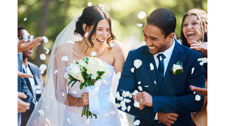 Guests throwing confetti over bride and groom as they walk past after their wedding ceremony. Joyful young couple celebrating their wedding day