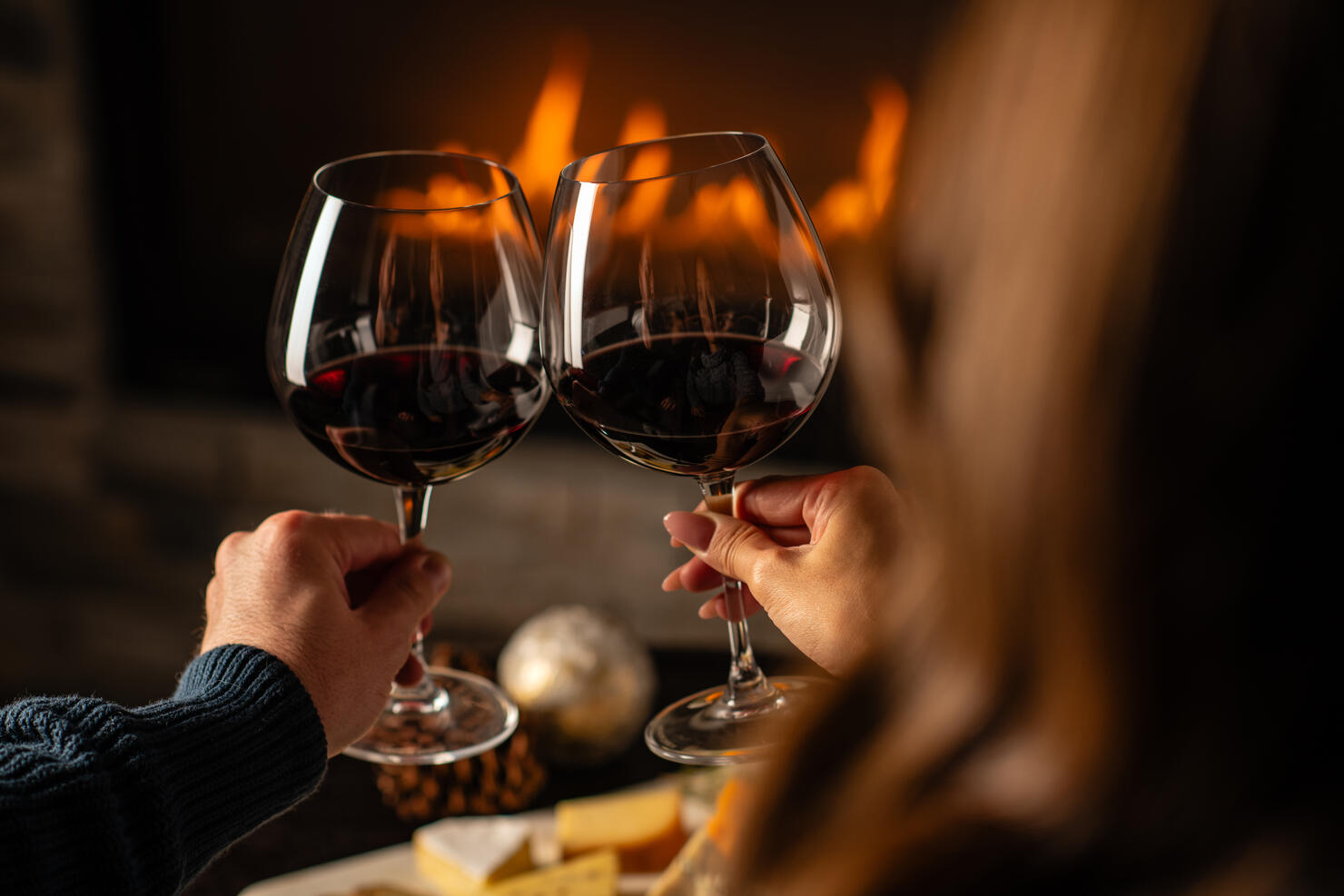 Close up of couples hands cheering with wine glasses