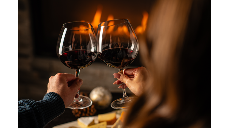 Close up of couples hands cheering with wine glasses