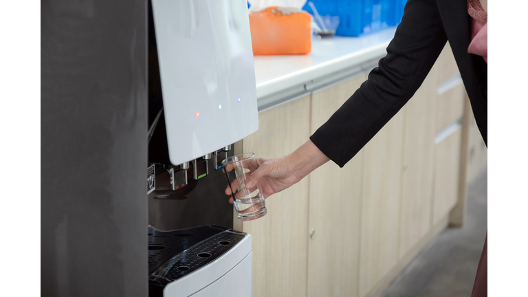 Hand holding glass filling cool water from water dispenser