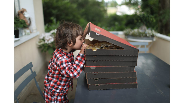 A 3 years old boy opening pizza boxes