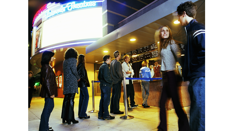 Multi-ethnic teens (14-18) lining up to buy movie tickets