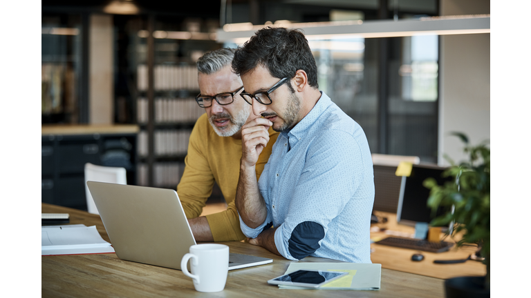 Businessmen using laptop at desk