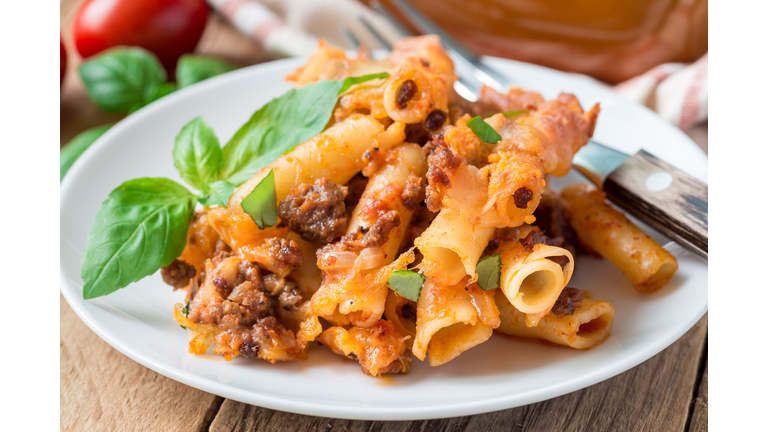 Ziti bolognese on white plate, pasta casserole with minced meat, tomato sauce and cheese, horizontal