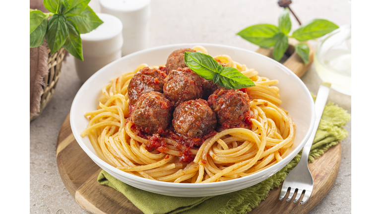 Spaghetti and beef Meatballs with tomato sauce in white dish on wooden rustic board, Italian-American food. Close-up.