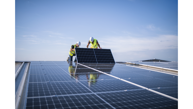 Two engineers installing solar panels on roof.