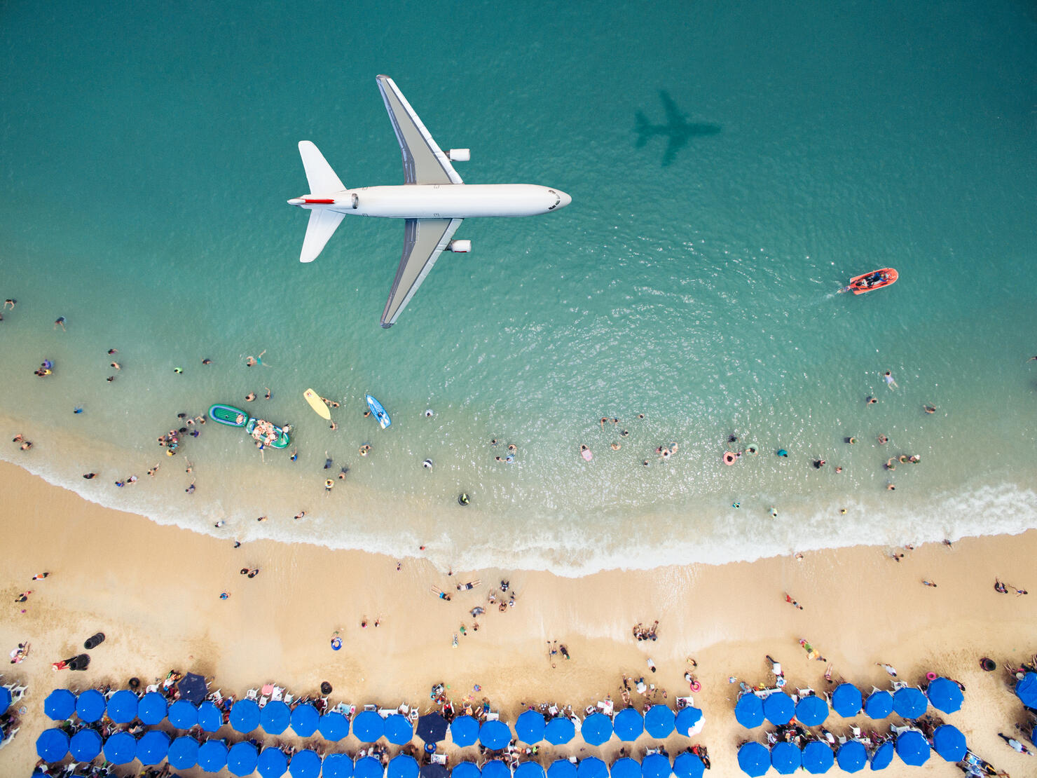 Airplane flying over a crowded beach