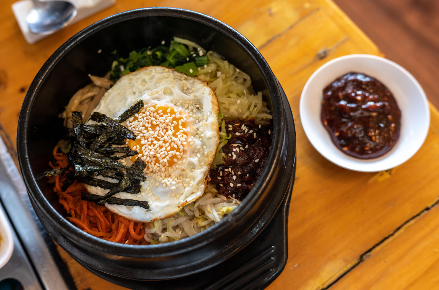 A traditional Korean food named Bibimbap a rice bowl topped with vegetables, meat with a fried egg etc.