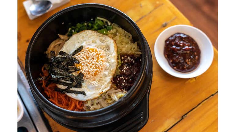 A traditional Korean food named Bibimbap a rice bowl topped with vegetables, meat with a fried egg etc.