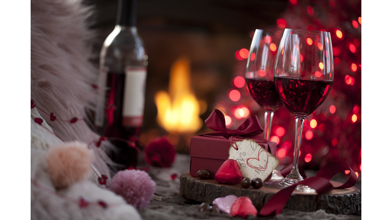 Valentine's Day Red Wine and a Gift with Chocolates in Front of the Fireplace