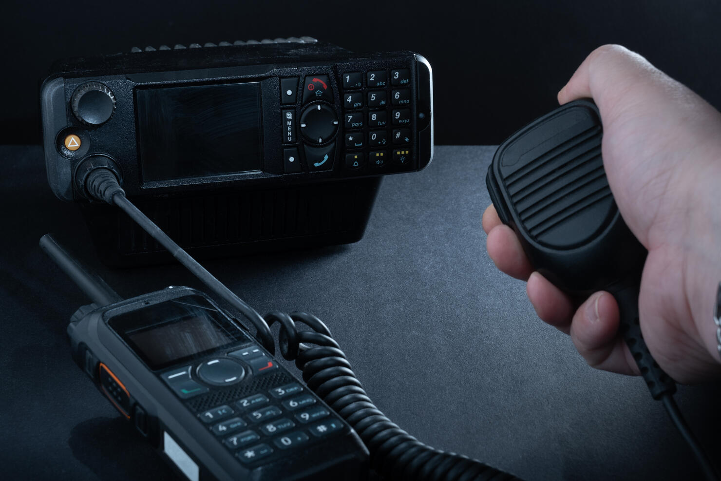 Closeup of pair of mobile two-way radios for Amateur radio operators against dark background.