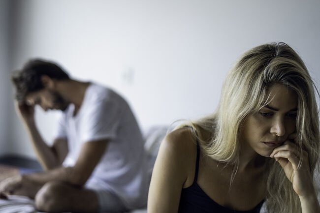 Upset couple sitting in bedroom