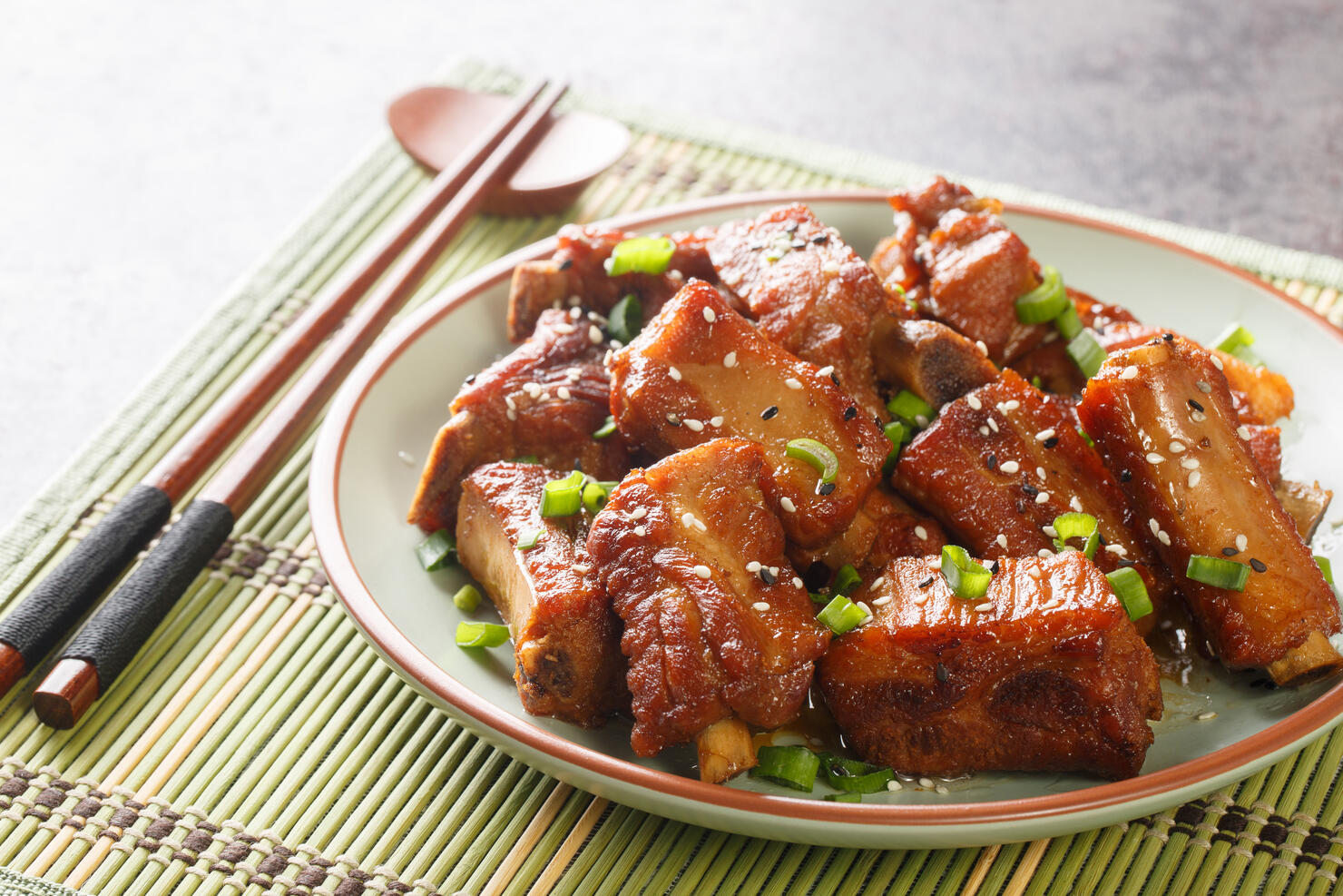 Chinese sweet and sour ribs with green onion and sesame close-up in a plate. Horizontal