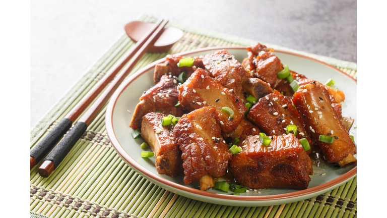 Chinese sweet and sour ribs with green onion and sesame close-up in a plate. Horizontal