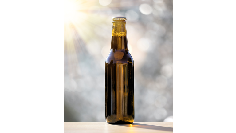 Outdoor beer bottle lit by sunlight.