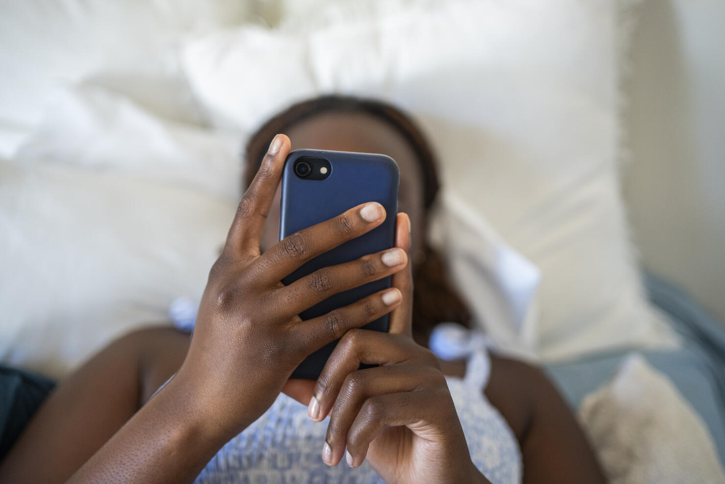 Teenage girl using a phone while lying on her bed