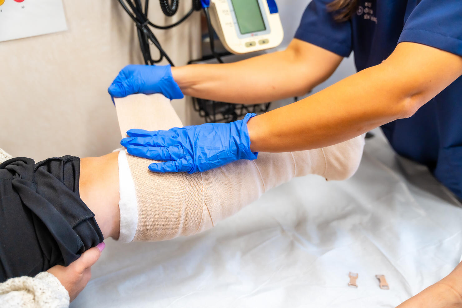 Detail of a nurse putting bandages all over the foot of a patient sitting on the stretcher. Health center or emergency hospital