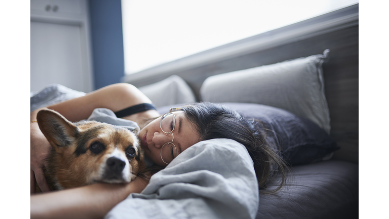 Mid adult woman lying in bed with dog