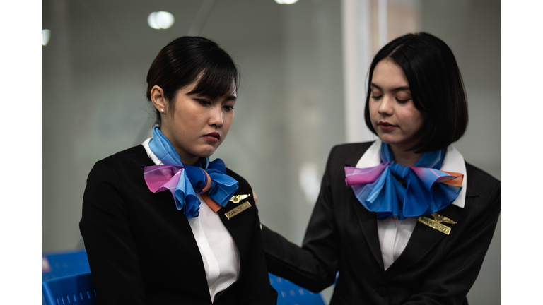 Unemployed young Asian air hostess stress sitting in the airport after last flight. Flight attendant feeling sad and worried about losing her job. Unemployment and the economic crisis from coronavirus