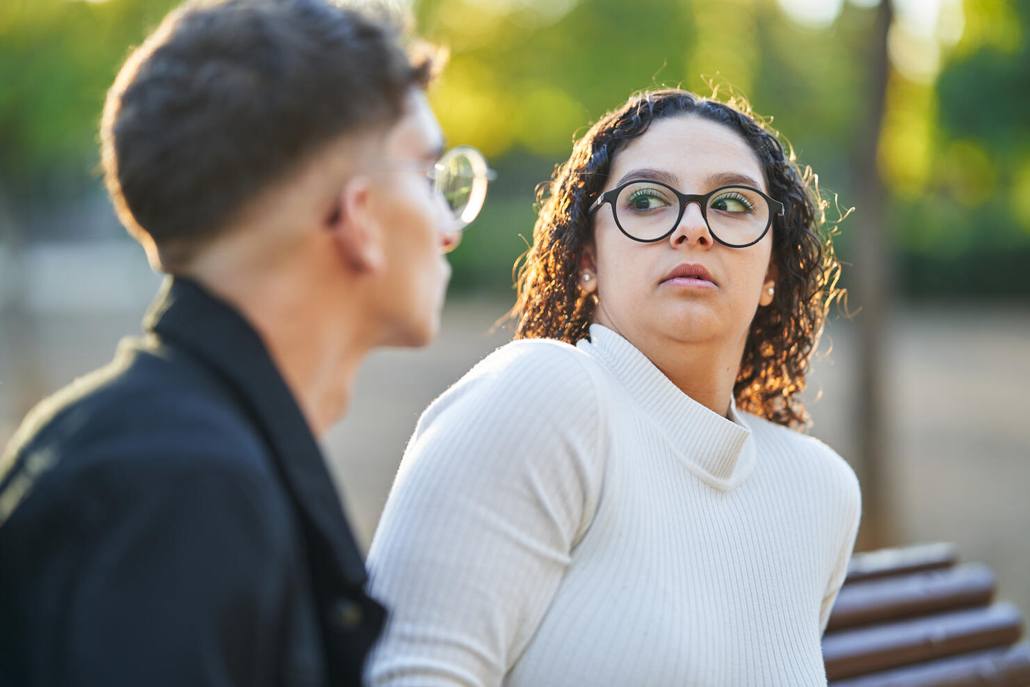 Woman keeping distance and rejecting a man while having a date together in a park.
