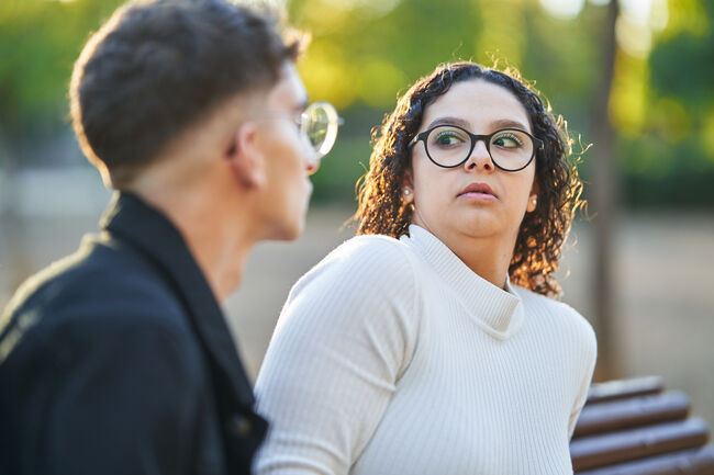 Woman keeping distance and rejecting a man while having a date together in a park.