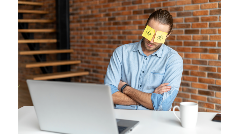 Young bearded office worker napping at work