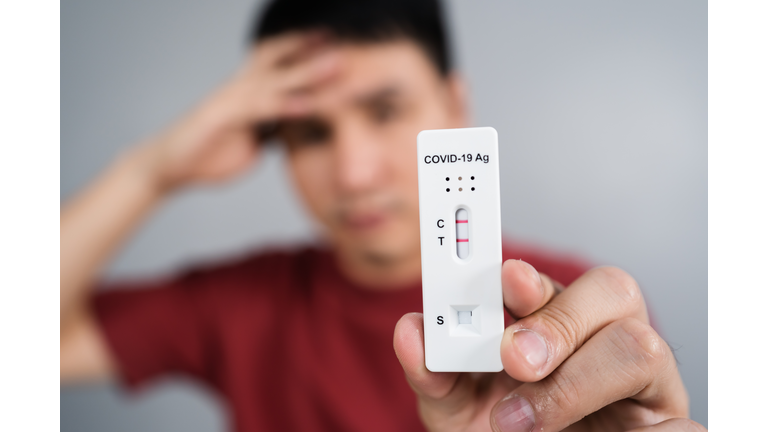 stressed man holding Coronavirus(Covid-19) positive test result with Antigen Rapid Test kit (ATK)