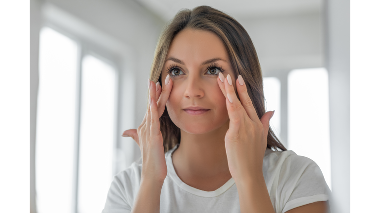 Applying moisturizing cream on under eye skin