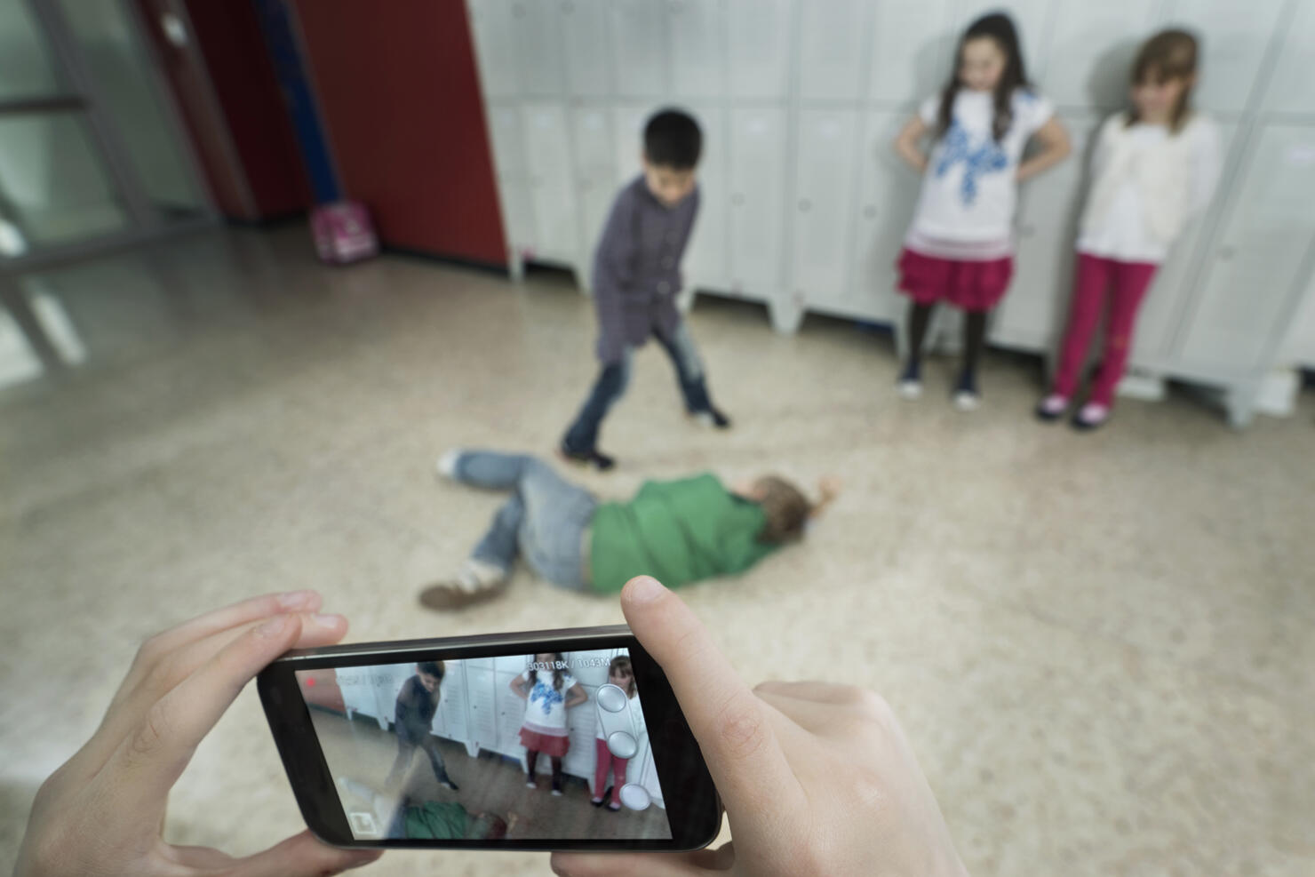 Persons hand filming two schoolboys fighting in school corridor with mobile phone, Bavaria, Germany
