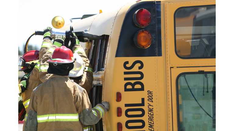 Firemen rescuing students from wrecked school bus