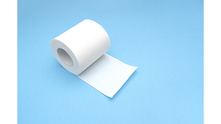 White blank roll of toilet paper with long sheet as mockup, on blue background, top view