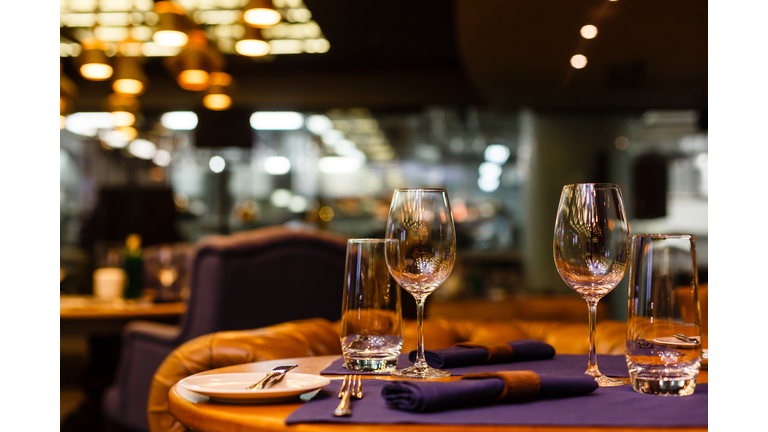 Two empty wine glasses sitting in a restaurant on a warm sunny afternoon.