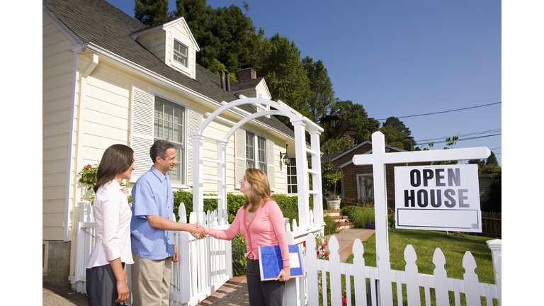 Couple shaking hands with real estate agent at open house