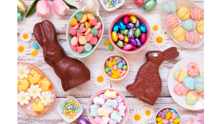Easter candy table scene over a white wood background