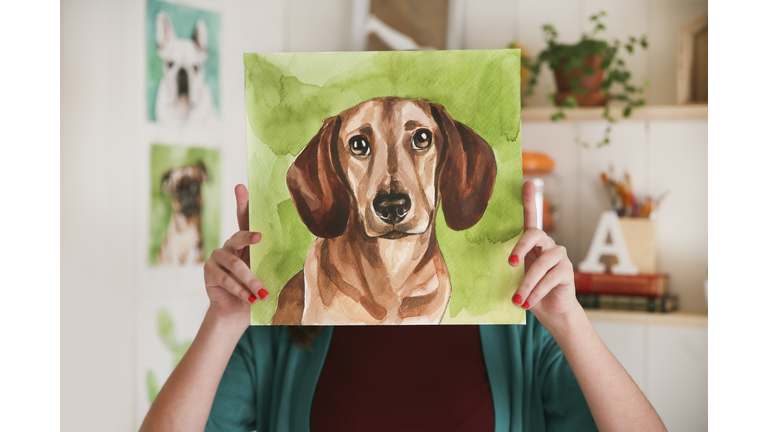 Artist hiding behind aquarelle of a dachshund