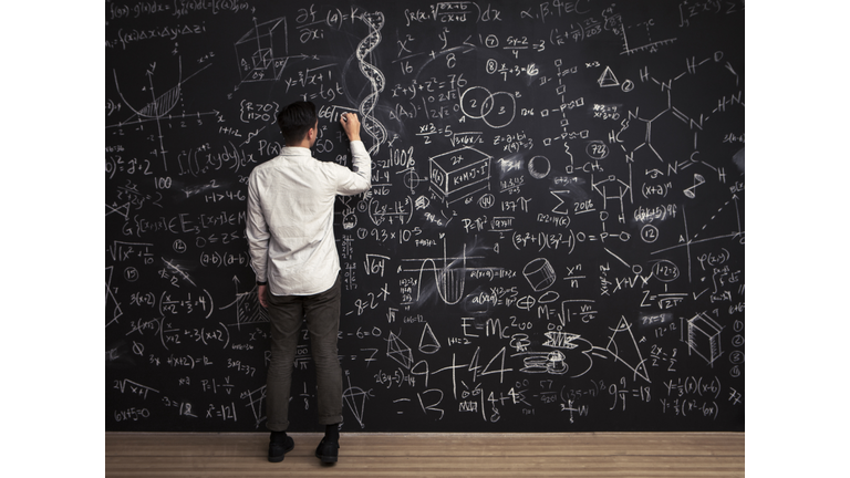 Man writes mathematical equations on chalkboard
