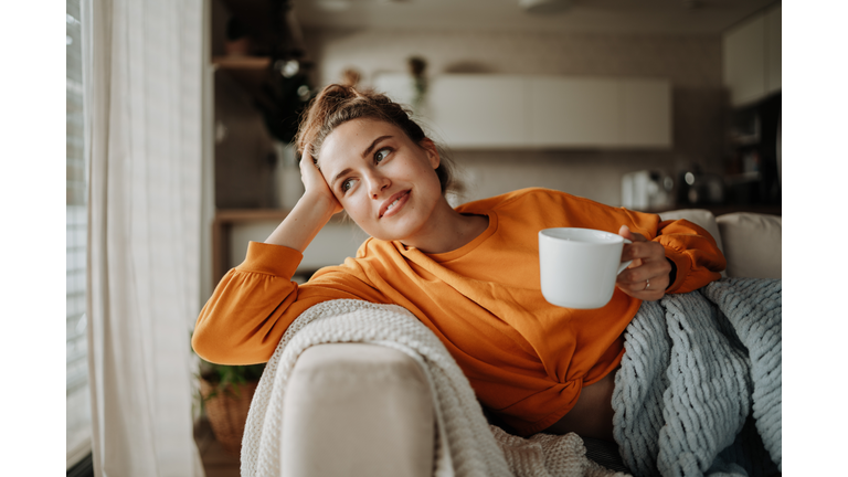 Young woman resting on sofa with cup of tea.