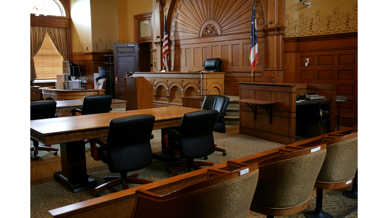 An empty, brown-paneled courtroom with flags