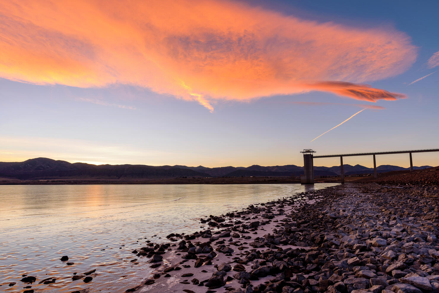 Sunset Chatfield Reservoir - Colorful winter sunset clouds rolling over frozen Chatfield Reservoir at foothill of front range of Rocky Mountains.