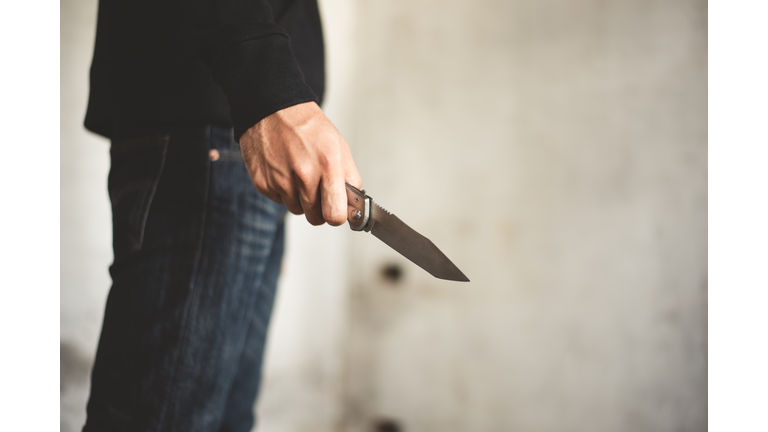 Close up of man holding knife in abandoned house. Terrorist and Robber concept. Police and Soldier. Weapon and armed theme